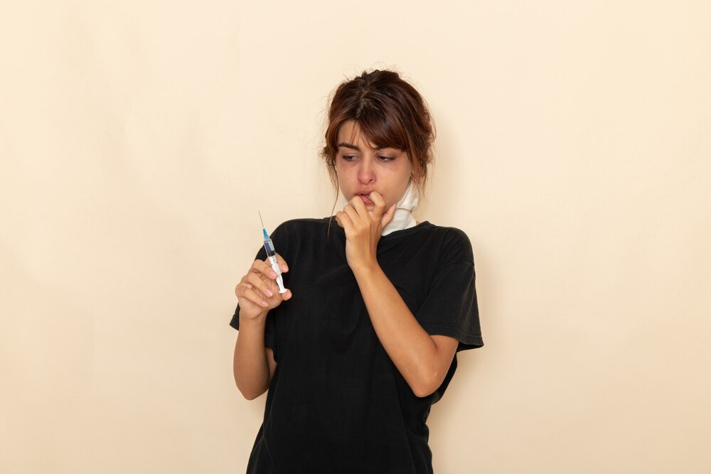 Front view sick young female feeling ill and holding injection on a white surface